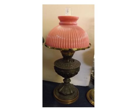 Cast pewter oil lamp with embossed decoration on a turned circular base, ribbed cranberry shade, 22ins tall  