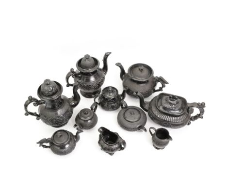 Early 19th century and later black basalt tea wares, mostly with relief or engine-turned bodies, including four large teapots