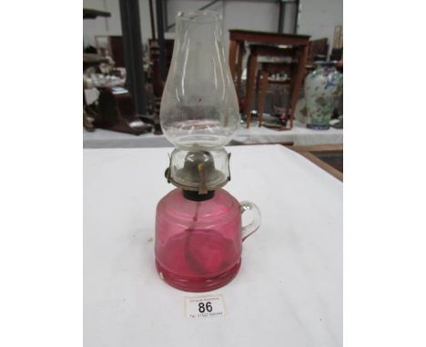 A cranberry glass hand oil lamp with chimney