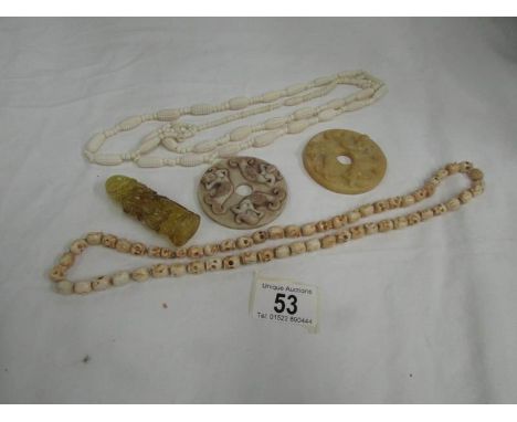 2 necklaces, 2 carved discs and one other item