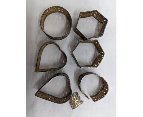 A set of six silver coloured metal filigree napkin rings, consisting of two heart shaped, two circular and two hexagonal, 88.