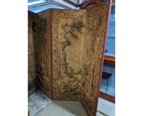 A late 19th/early 20th century four fold tapestry panel screen with red leather backing decorated with brass studs, each pane