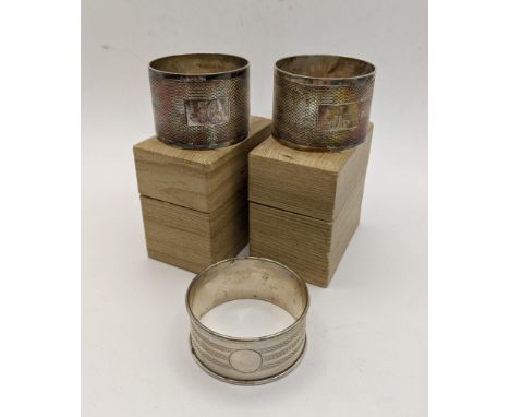 A pair of cased silver napkin rings hallmarked Sheffield 1931 together with another napkin ring with machine turned design to