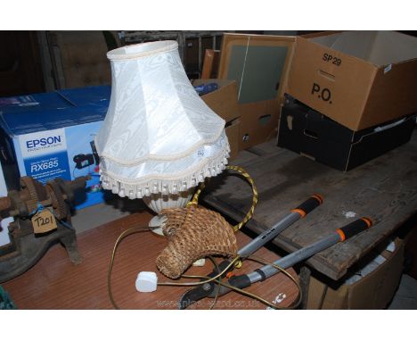 A table lamp with shade, garden pruners and a wicker basket.