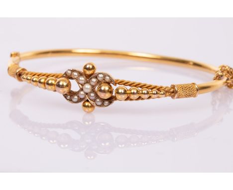 A 9ct yellow gold and seed pearl hinged bangle with central pearl set figure of eight, approximately 6.2gm in a fitted Carrin