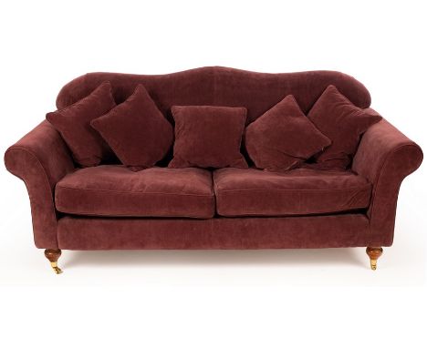 An upholstered sofa covered in mauve material and raised on turned feet with castors CONDITION REPORT: Condition information 