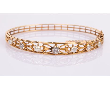 A 14k yellow gold hinged bangle set with three diamonds interspersed by pearls in a pierced surround, the clasp engraved fain
