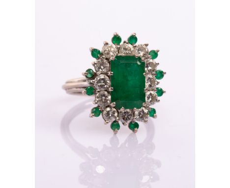 An emerald and diamond cluster ring, the central step cut emerald of approximately 2.35ct to a surround of twelve brilliant c