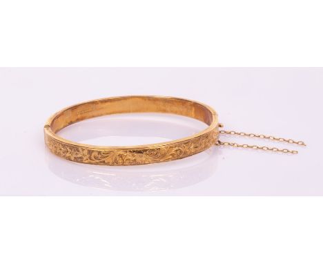 A 9ct yellow gold hinged bangle, one half engraved foliate decoration, internal size 5cm x 5.8cm CONDITION REPORT: Safety cha