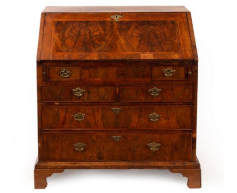 A George I walnut bureau, cross banded and with feather banding, fitted interior with well beneath the fall and an arrangemen