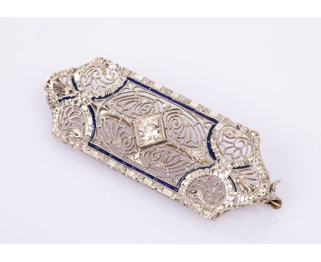 An Art Deco diamond and 14k white gold brooch, the central diamond to a filigree surround highlighted in enamel, 44mm x 15mm,