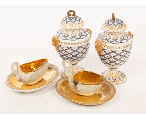 A pair of 19th Century porcelain urns and covers, decorated blue trellis designs, moulded with mask head handles and gilt, 18