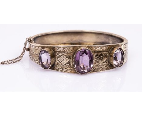 A silver gilt and amethyst hinged bangle, the three oval amethysts to an engraved silver bracelet, internal size 5cm x 6cm CO