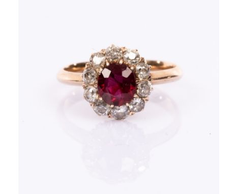 A ruby and diamond cluster ring, the central ruby to a surround of ten diamonds, claw set to a yellow metal shank, size K CON