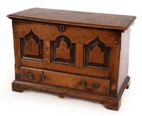 An early 18th Century oak coffer bach, the hinged cover with moulded border, the front carved three arches with drawer beneat