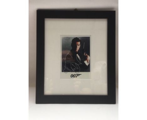 A framed and glazed signed photo of Pierce Brosnan as James Bond, approx 30cm x 35cm. Comes with COA from a UACC registered m