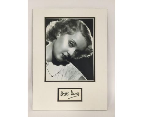 A mounted display of Bette Davis with signature and photographic print. Approx 29cm x 39cm. No COA.