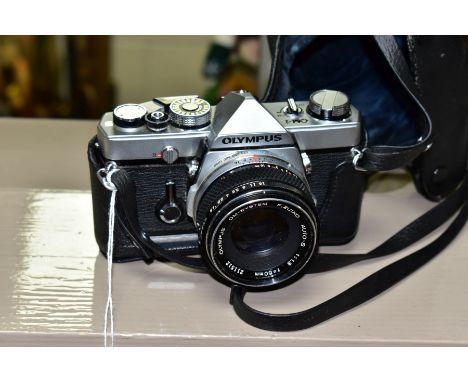 AN OLYMPUS OM-1 35MM SLR CAMERA, fitted with an Olympus Zuiko 50mm f1.8 lens, together with a leather case, condition: dusty 