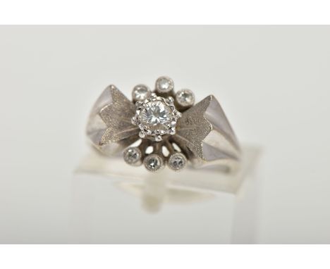 A WHITE METAL DIAMOND RING, abstract bow style ring set centrally with a round brilliant cut diamond, raised between a textur