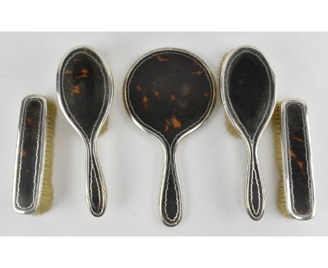 A George V hallmarked silver &amp; tortoise shell dressing table set. The set to include a hallmarked silver mirror, two brus