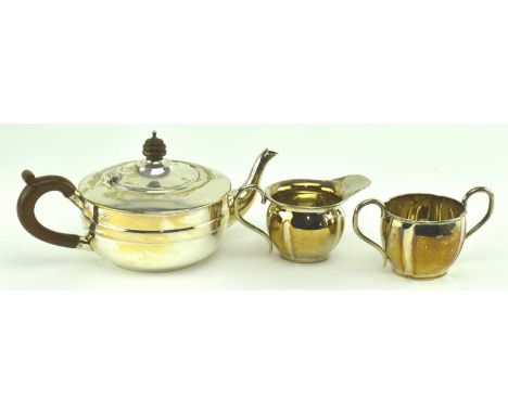 A three piece hallmarked silver part tea service. The lot to include a hallmarked silver with wooden handle teapot, hallmarke