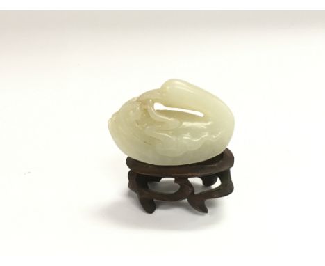 A jade figure of a duck raised on a hardwood stand, approx length 4.5cm.