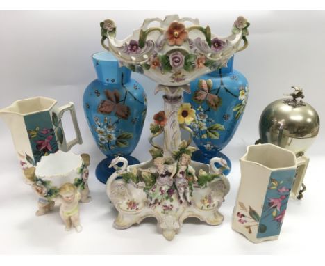 A porcelain centrepiece , a pair of blue art glass vases, a ceramic pot supported by three cherubic figures and other items.