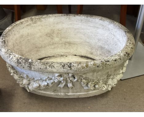 A large vintage oval concrete planter with wreath and bow design.79 x 56 x 35cm