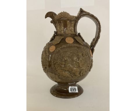 A Castle Hedingham pottery, The Essex jug, dated 1891, bulbous body covered in a brown glaze, moulded with panels of figures,
