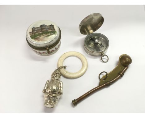 A small circular porcelain box, bosun's whistle, silver plated teething ring and a pocket compass (4).