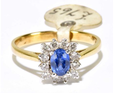 An 18ct yellow gold sapphire and diamond cluster ring, centred with a pale blue sapphire within a border of twelve brilliant 