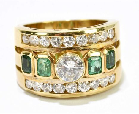 A yellow metal diamond and emerald three band ring, centred with a round brilliant cut collet set stone approx. 0.60cts, flan