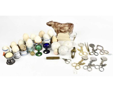 A collection of assorted ceramic hen eggs, with three carpet bowls, a moulded glass penny lick, egg cutters, a James MacIntyr