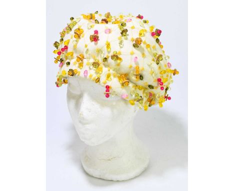 CHRISTIAN DIOR, PARIS, NEW YORK; a 1950s cream wool felt lady's hat covered with green, yellow and pink beads on a yellow emb