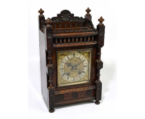 A late 19th century German oak cased mantel clock with four turned finials above brass face set with silvered chapter ring be