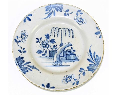 An 18ct century English Delftware plate decorated with a peony and rockwork in a fenced garden, diameter 13.5cm.Condition Rep