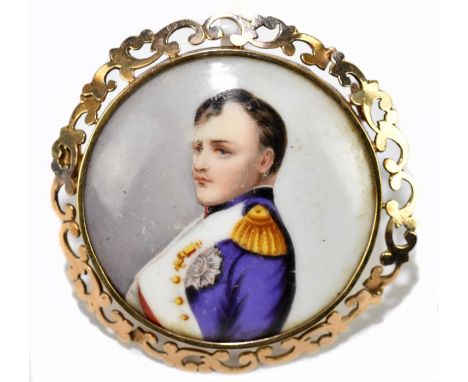 A circular yellow metal framed porcelain brooch depicting the profile portrait of Napoleon, within a scroll pierced frame, un