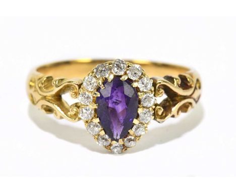 A yellow metal ring with amethyst and diamond pear shaped plaque set within scrolling shoulders with the band stamped '18', s