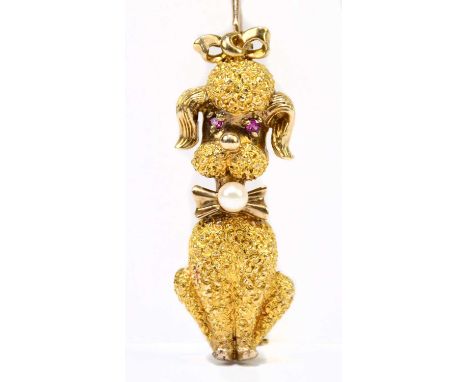 A novelty 9ct textured yellow gold brooch in the form of a seated poodle, with ruby eyes and pearl to the bow collar, length 