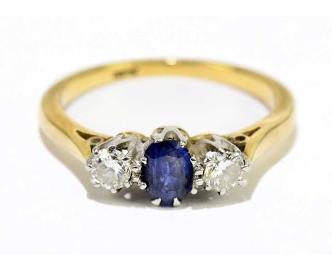 An 18ct yellow gold sapphire and diamond three stone ring with central oval sapphire flanked by twin round brilliant cut diam