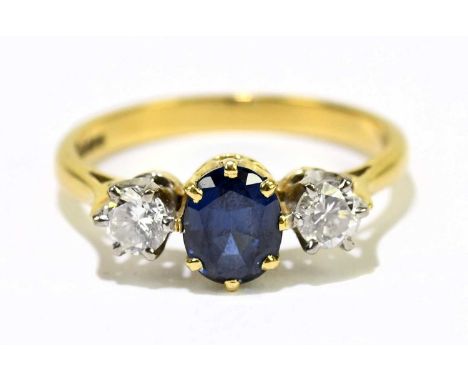 An 18ct yellow gold sapphire and diamond three stone ring, the eight claw set central sapphire flanked by twin round brillian