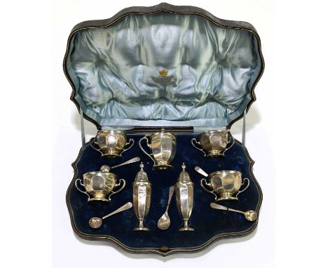 A George V hallmarked silver seven piece cruet, comprising wet mustard, two pepperettes and four twin handled salts, with fou