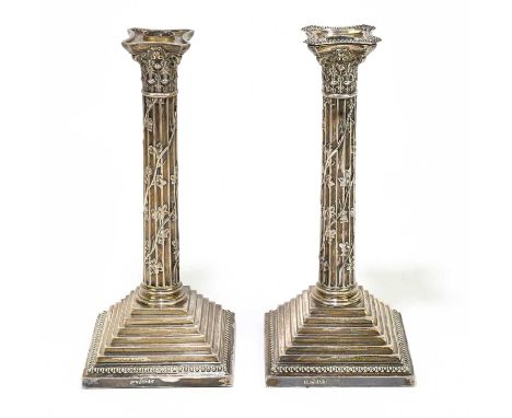 MARK WILLIS; a pair of Victorian hallmarked silver Corinthian column candlesticks, the cast beaded rims and trailing floral d