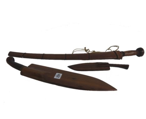One large and one small coconut knife with steel blades and hardwood handles and sheaths, 20th century, the larger 38cm long,