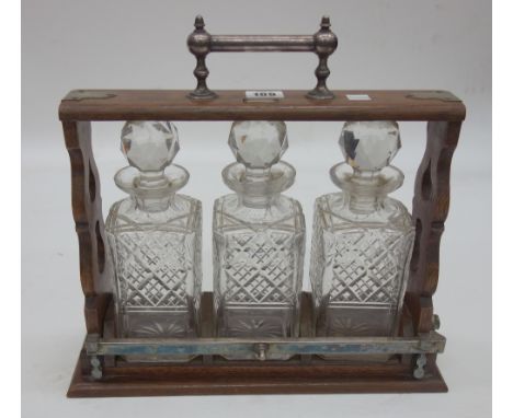 A late Victorian electroplate mounted oak tantalus, labelled Joseph Ridge & Co, Sheffield, fitted with three square section c
