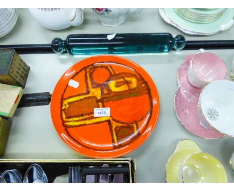 A VICTORIAN GLASS ROLLING PIN AND POOLE POTTERY PLATE WITH ORANGE GROUND AND ABSTRACT DECORATION 