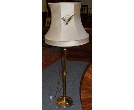 A brass standard lamp, telescopic central pole, and raised upon claw feet 