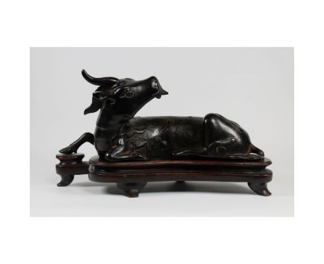 A Chinese Yuan dynasty (1271-1368) bronze recumbent xiniu mirror stand. The finely cast stand is in the shape of a recumbent 