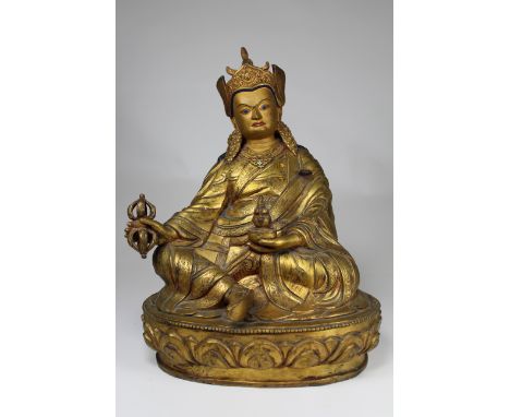 Large Antique Tibetan Gilt Bronze Figure of Padmasambhava. Seated in lalitasana on a lotus base, his right hand holding a vaj