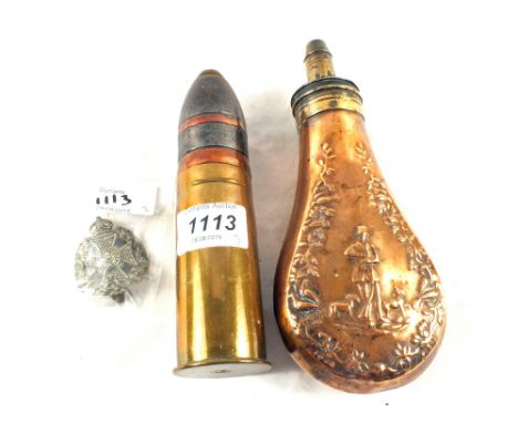 A Copper powder flask with shell case and head, plus a cap badge